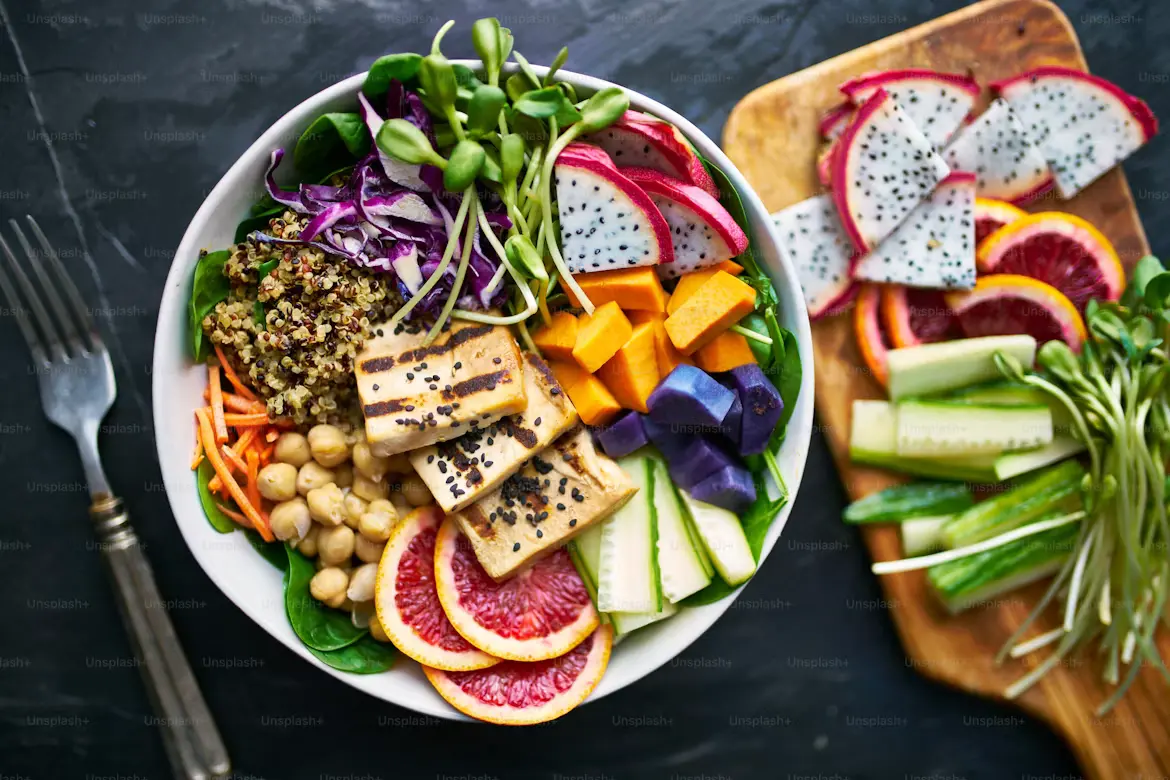 Healthy quinoa Buddha bowl with chickpeas, avocado, cherry tomatoes, cucumber, carrots, and red cabbage.